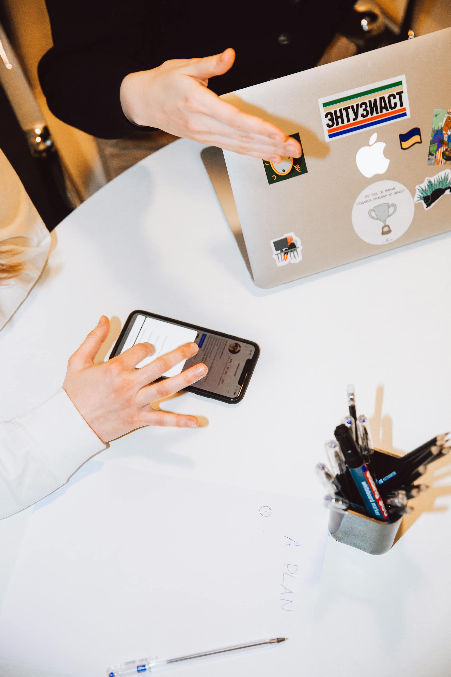 Two people collaborating with laptops and smartphones in a modern workspace setting.